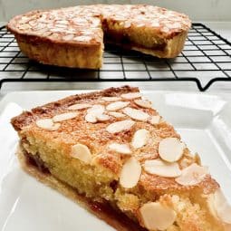 A slice of Bakewell Tart with the tart in the background