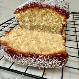 Jam & Coconut Cake sliced on a wire rack